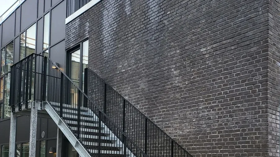 Nyere erhvervsbyggeri med mørk murstensfacade og udvendig trappe
